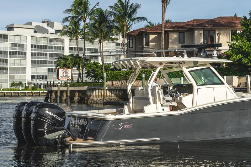 Slide: The Image of 2021 Scout 355 LXF boat docked near waterfront homes and palm trees. - 8