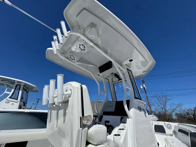 Slide: The Image of 2025 Tidewater 232 CC Adventure boat with T-top and rod holders under clear blue sky. - 18