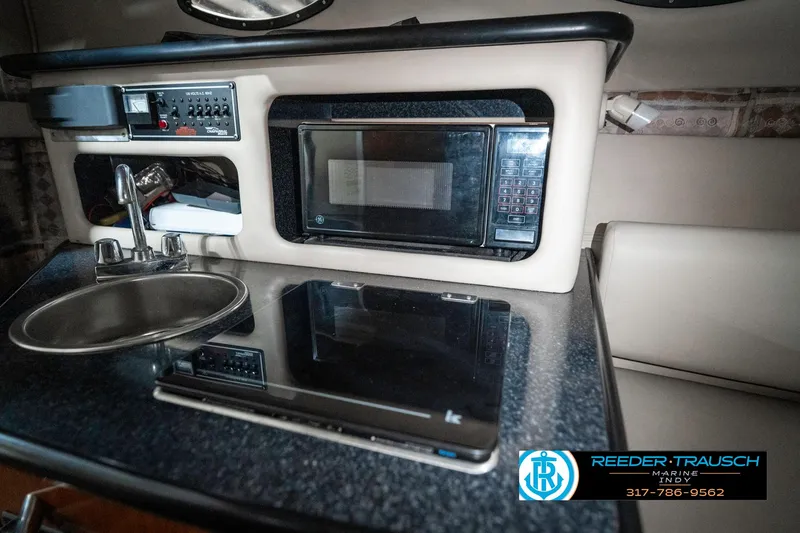 Slide: The Image of 2000 Chaparral Signature 240 boat interior with kitchenette, featuring a microwave and sink. - 30