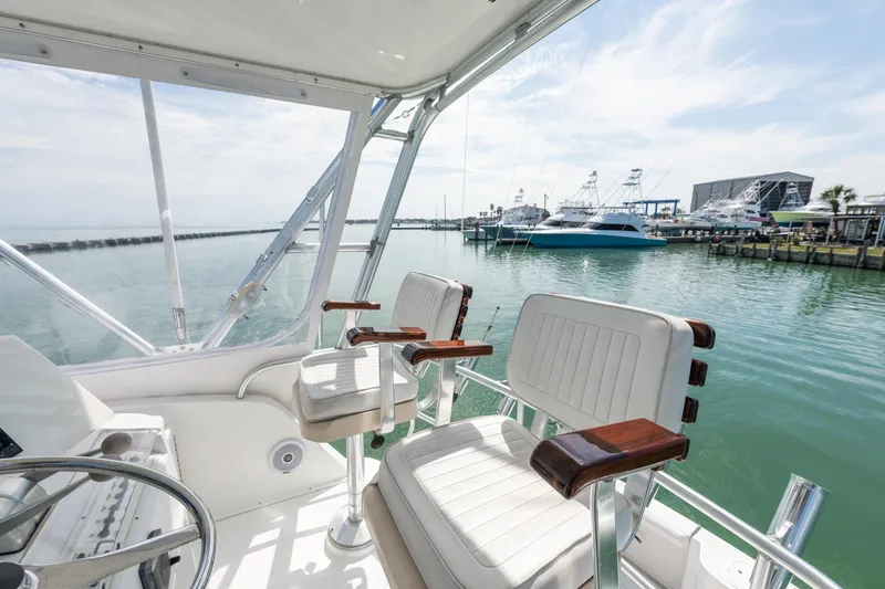 Slide: The Image of Cabo Convertible 2000 boat interior with marina view, featuring white seating and clear skies. - 11