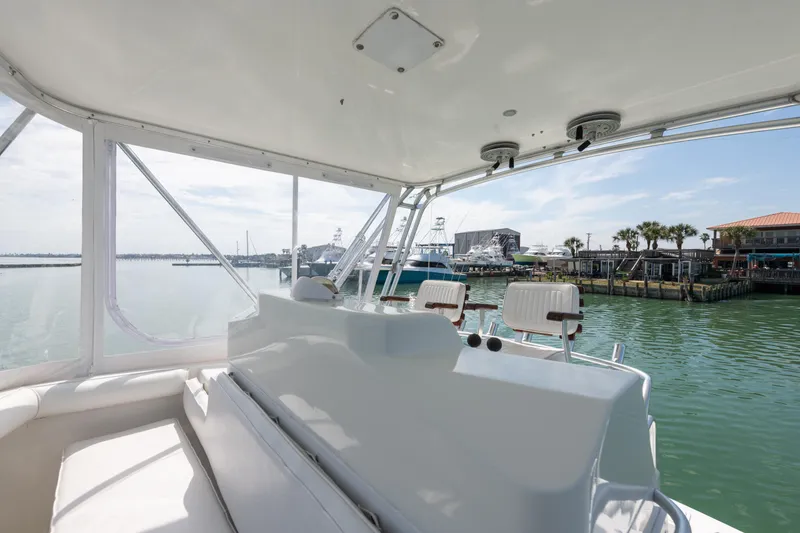Slide: The Image of 2000 Cabo Convertible boat interior with marina view, featuring seating and helm station. - 13