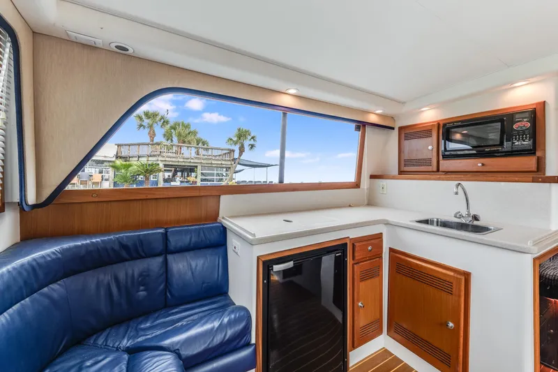 Slide: The Image of Interior of a 2000 Cabo Convertible yacht with blue seating and kitchenette. - 15