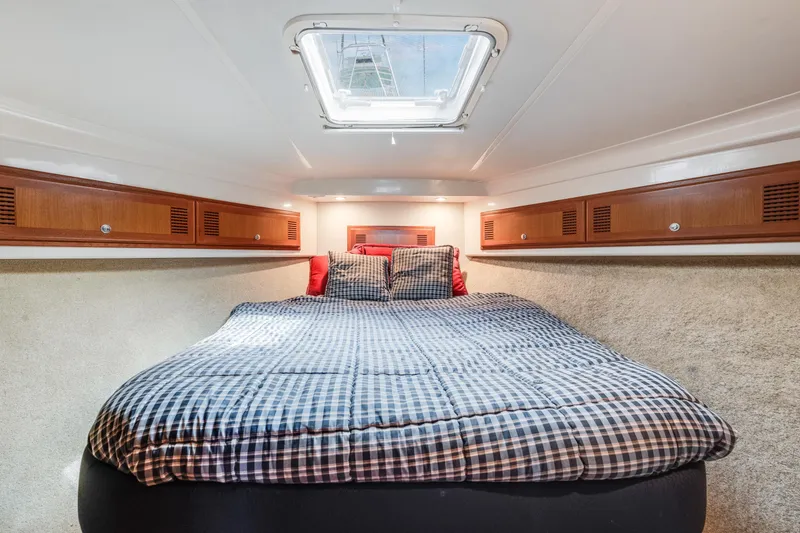 Slide: The Image of Cozy cabin interior of 2000 Cabo Convertible boat with skylight and checkered bedding. - 19