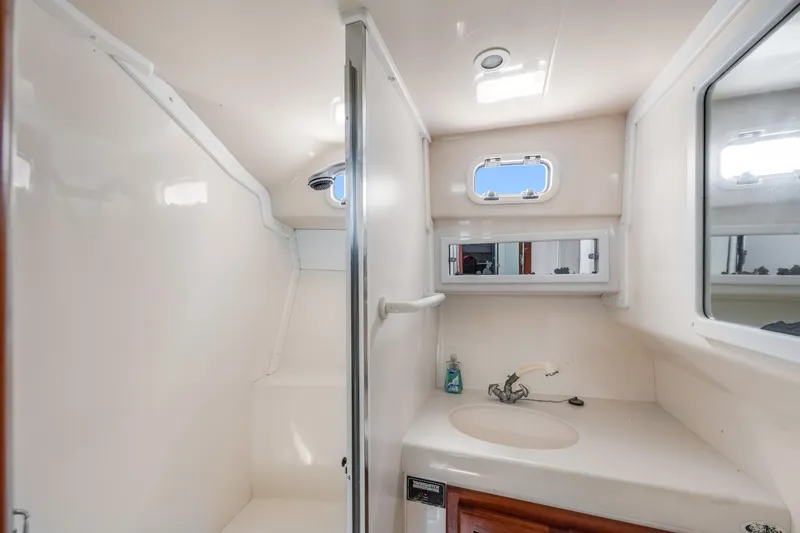 Slide: The Image of 2000 Cabo Convertible boat bathroom with sink, mirror, and small window. - 24