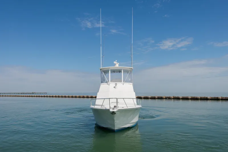 Slide: The Image of 2000 Cabo Convertible boat on calm water under clear blue sky. - 3