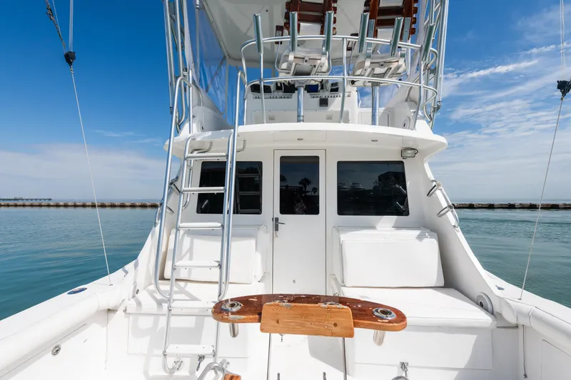 Slide: The Image of 2000 Cabo Convertible boat with fishing deck, ladder, and seating, under a clear blue sky. - 5