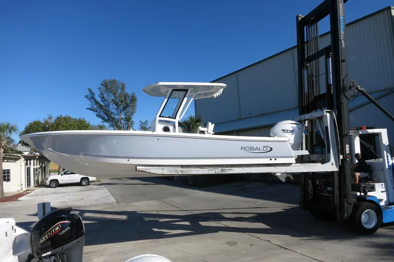 Slide: The Image of 2025 Robalo 266 Cayman boat lifted by forklift in outdoor setting. - 40