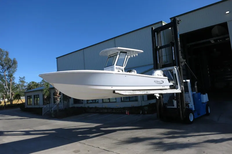 Slide: The Image of 2025 Robalo 266 Cayman boat lifted by forklift outside warehouse. - 41
