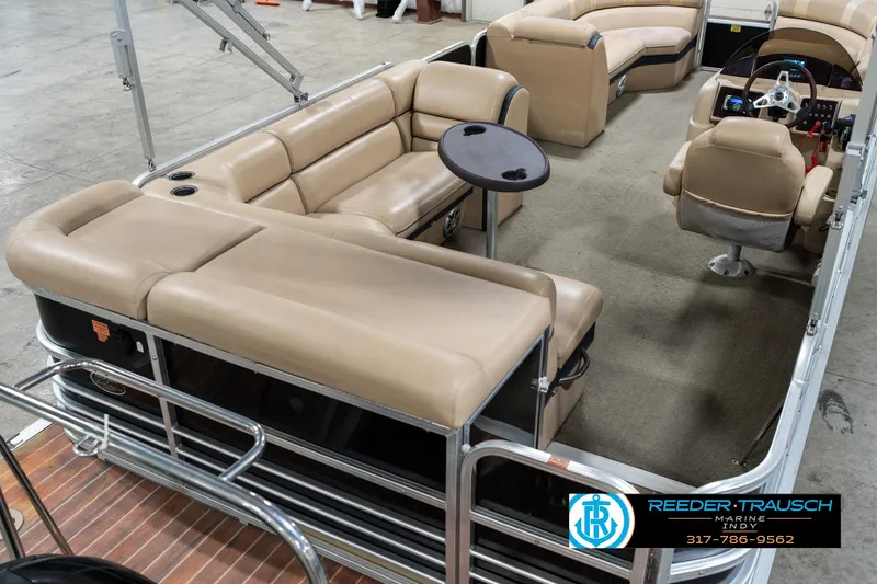 Slide: The Image of 2014 Bennington 522CR pontoon boat with beige seating and steering console, displayed indoors. - 14