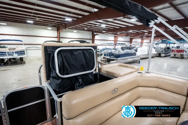 Slide: The Image of 2014 Bennington 522CR pontoon boat interior in showroom, featuring tan seating and storage area. - 31