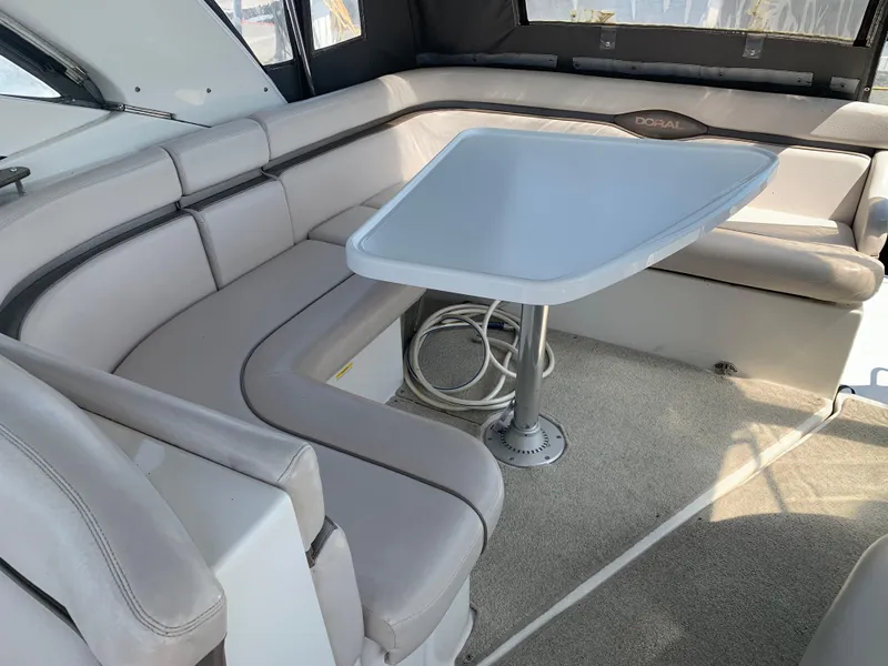 Slide: The Image of 2002 Doral 310se boat interior with beige seating and table. - 11
