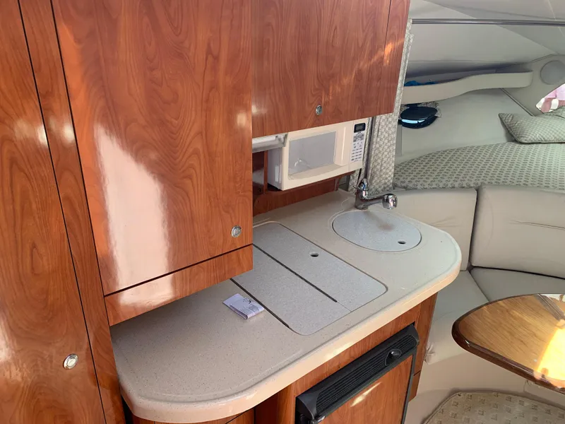 Slide: The Image of 2002 Doral 310se boat interior with kitchenette, featuring wood cabinets and a compact sink. - 15