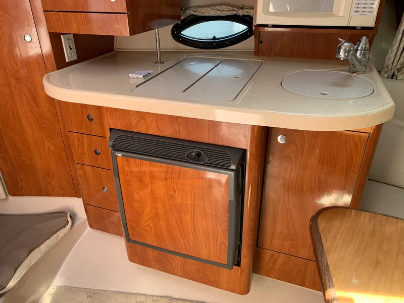 Slide: The Image of 2002 Doral 310se boat kitchen with wood cabinetry, sink, and compact fridge. - 19