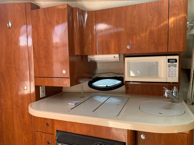 Slide: The Image of 2002 Doral 310se boat interior kitchen with wood cabinets, microwave, and sink. - 20