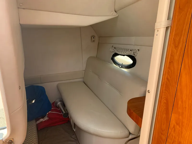 Slide: The Image of Interior cabin of 2002 Doral 310se boat with white seating and porthole window. - 21