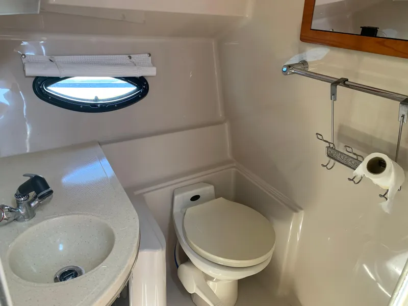 Slide: The Image of 2002 Doral 310se boat bathroom with sink, toilet, and porthole window. - 22
