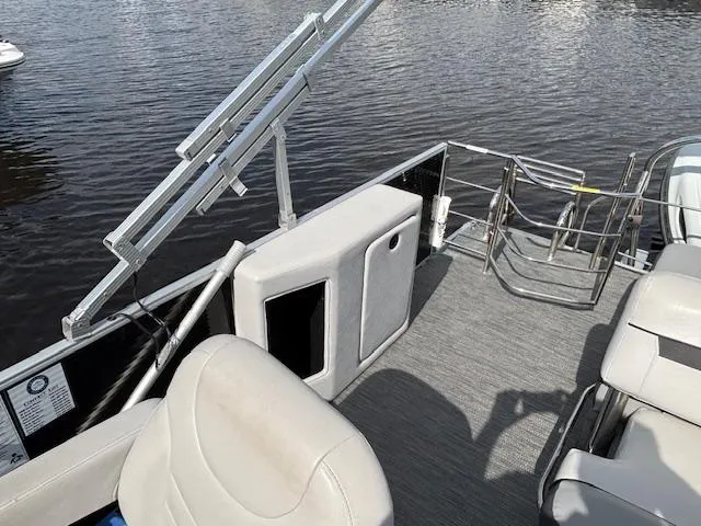 Slide: The Image of 2022 Sweetwater 2286 pontoon boat interior with seating and railing, on calm water. - 12