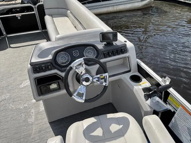 Slide: The Image of 2022 Sweetwater 2286 boat dashboard with steering wheel and controls on water. - 14
