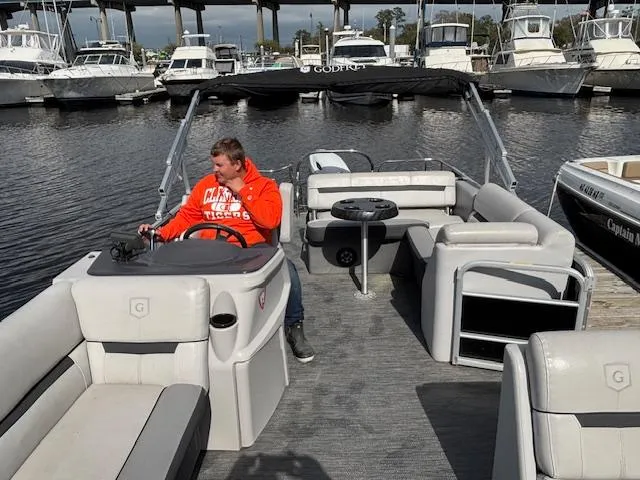 Slide: The Image of 2022 Sweetwater 2286 pontoon boat with person at helm, docked in marina. - 15