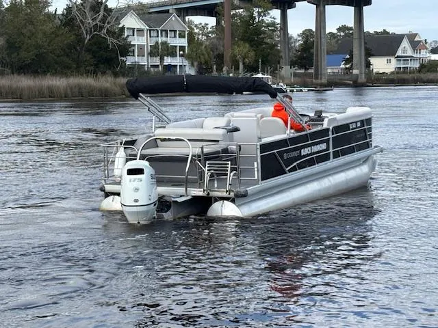 Slide: The Image of 2022 Sweetwater 2286 pontoon boat cruising on a river near residential area. - 3
