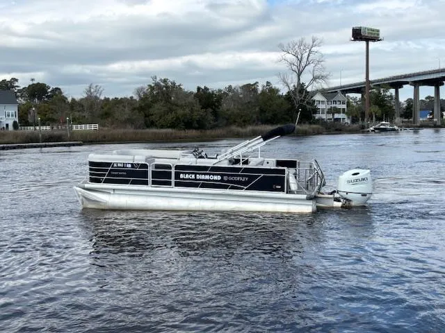 Slide: The Image of 2022 Sweetwater 2286 pontoon boat on a river with trees and a bridge in the background. - 5
