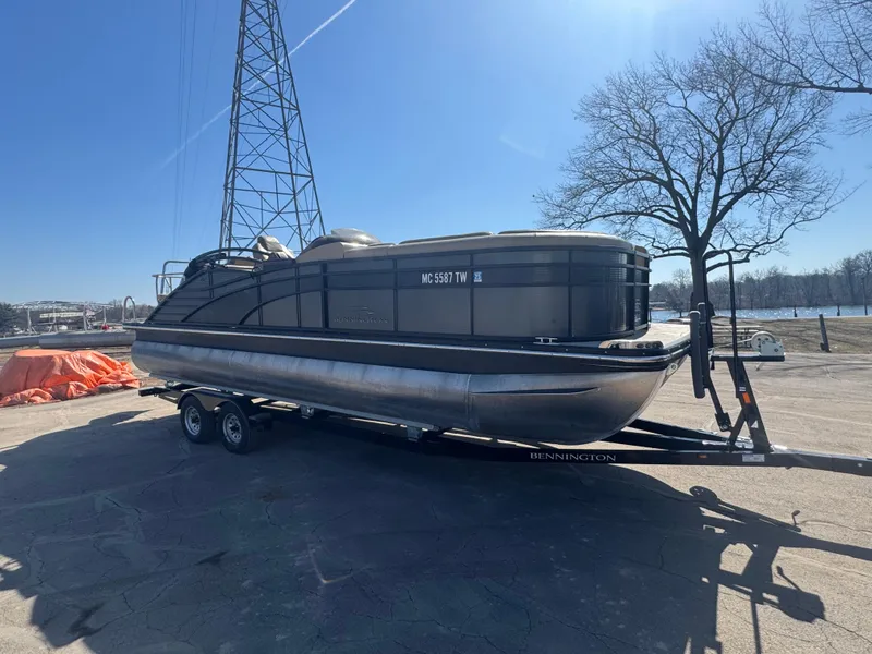 Slide: The Image of 2016 Bennington 2275 RCW pontoon boat on trailer, parked outdoors under clear sky. - 0