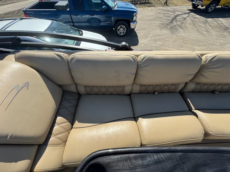 Slide: The Image of 2016 Bennington 2275 RCW boat with beige leather seating, parked near vehicles. - 11