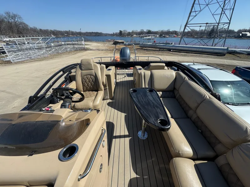 Slide: The Image of 2016 Bennington 2275 RCW pontoon boat with spacious seating and sleek design, docked by a lake. - 8