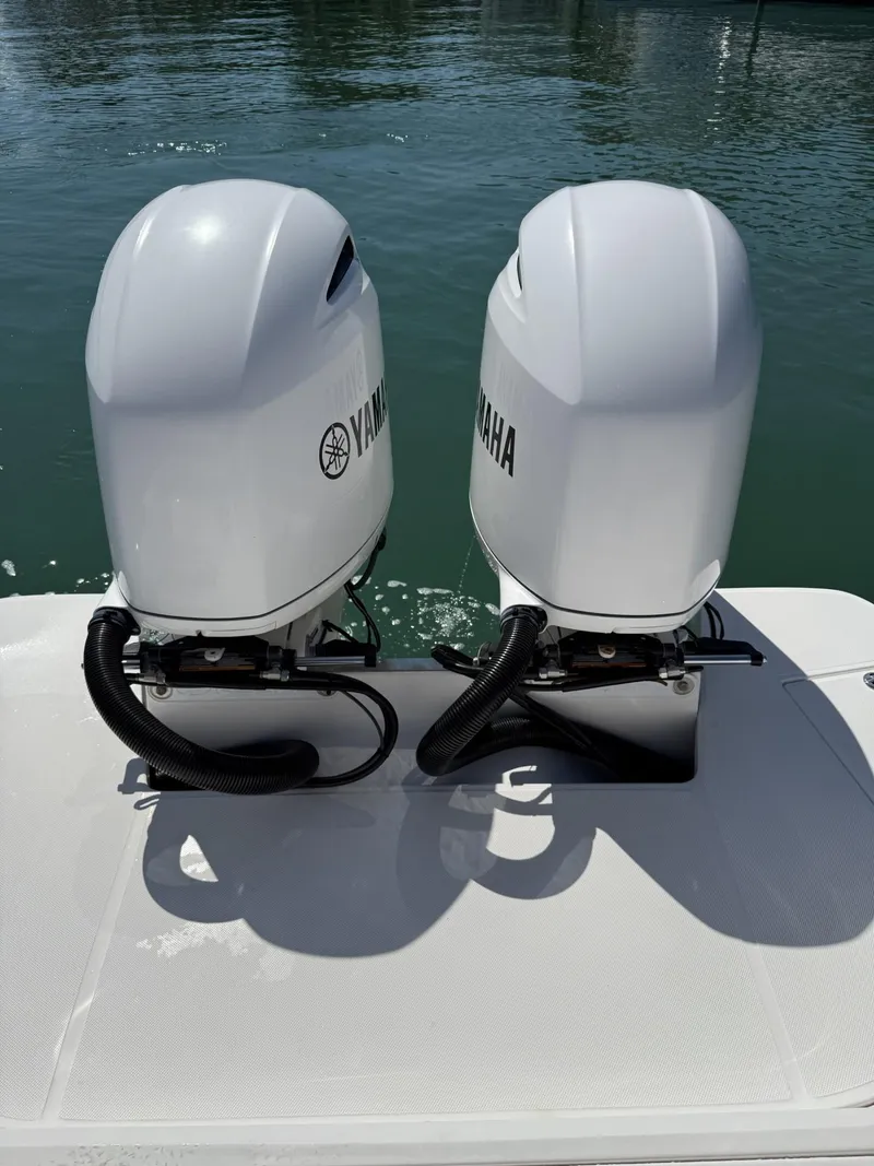 Slide: The Image of Twin Yamaha outboard engines on a 2019 Regal 29 OBX boat, docked on calm water. - 14