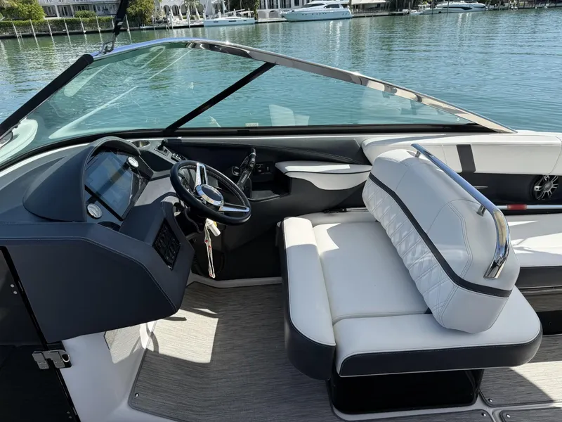 Slide: The Image of 2019 Regal 29 OBX boat interior with steering wheel and seating, docked by the water. - 20