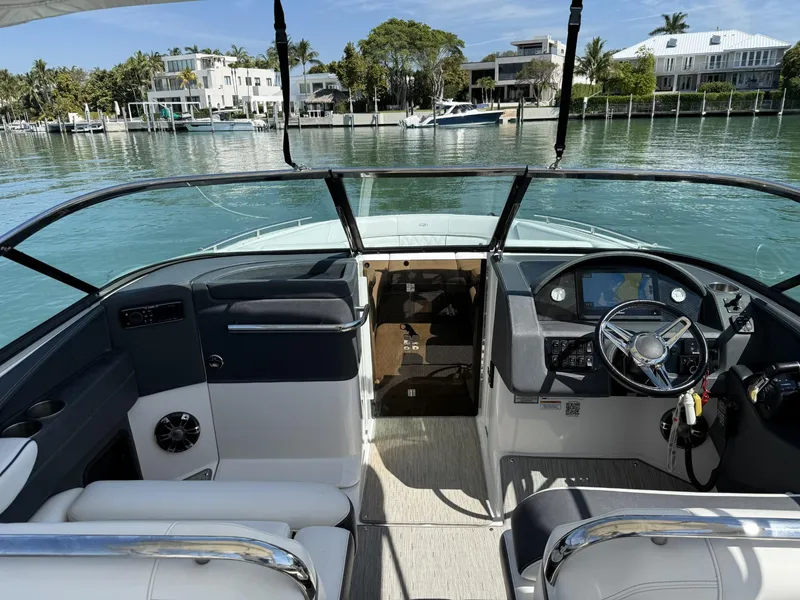 Slide: The Image of 2019 Regal 29 OBX boat interior with steering wheel, docked by waterfront homes. - 21