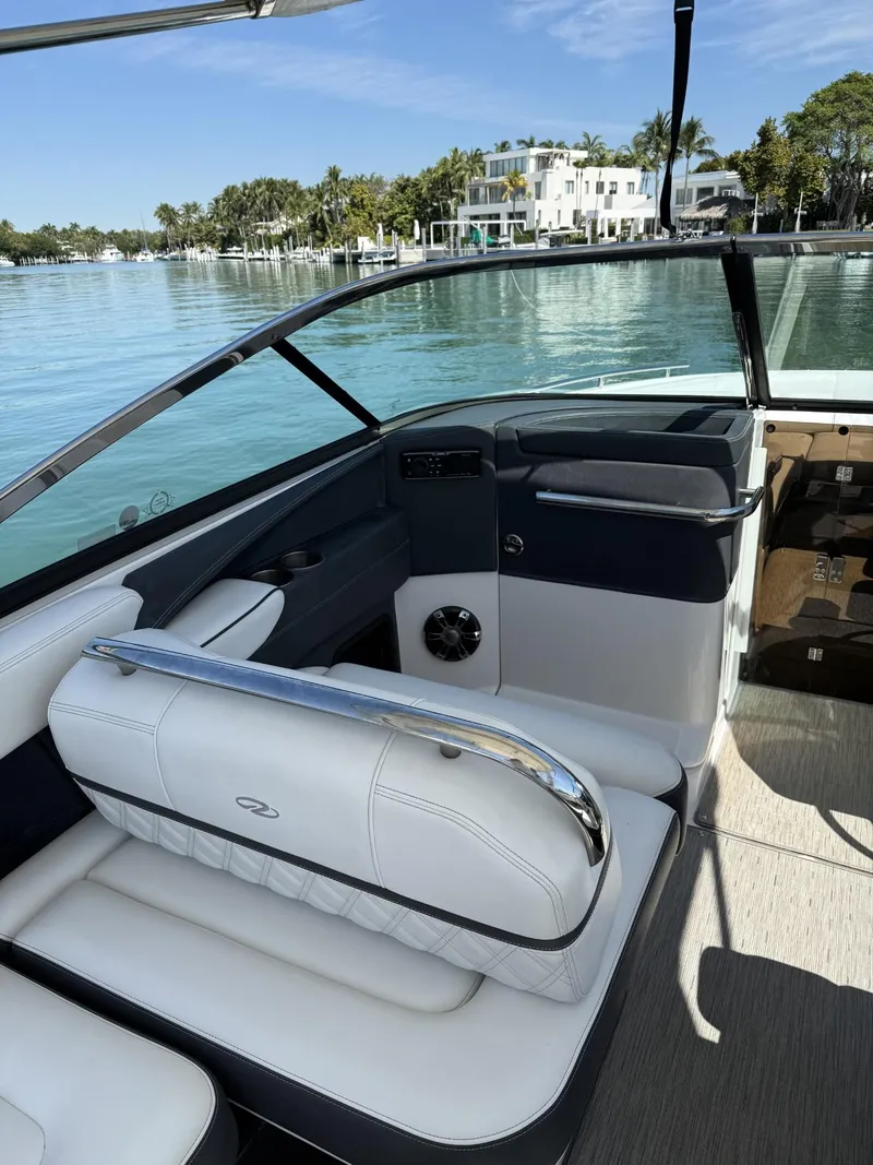 Slide: The Image of 2019 Regal 29 OBX boat interior with white seating, on a calm waterfront. - 22