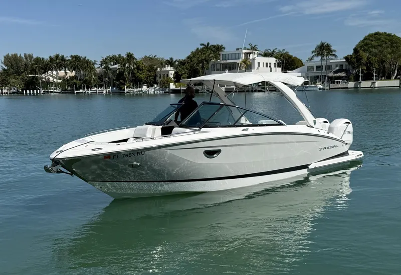 Slide: The Image of 2019 Regal 29 OBX boat on calm water, surrounded by waterfront homes. - 6