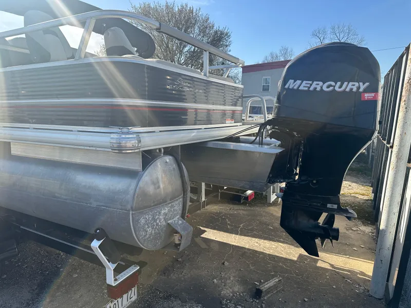 Slide: The Image of 2012 Sun Tracker Fishin' Barge 24 DLX with Mercury outboard motor, parked outdoors. - 2