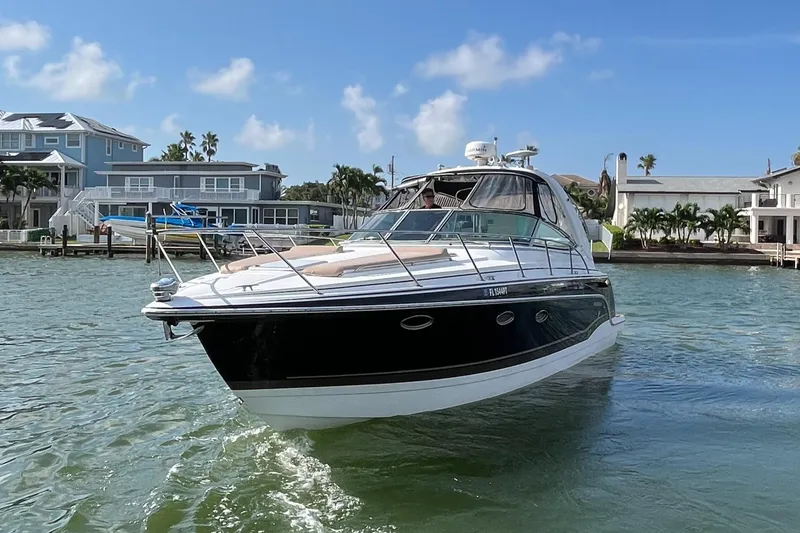 Slide: The Image of 2012 Formula 31 PC boat cruising in a scenic waterfront area with houses. - 2