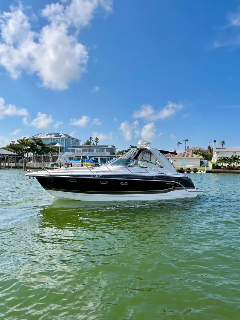 Slide: The Image of 2012 Formula 31 PC boat cruising on a sunny day with blue sky and waterfront homes. - 8