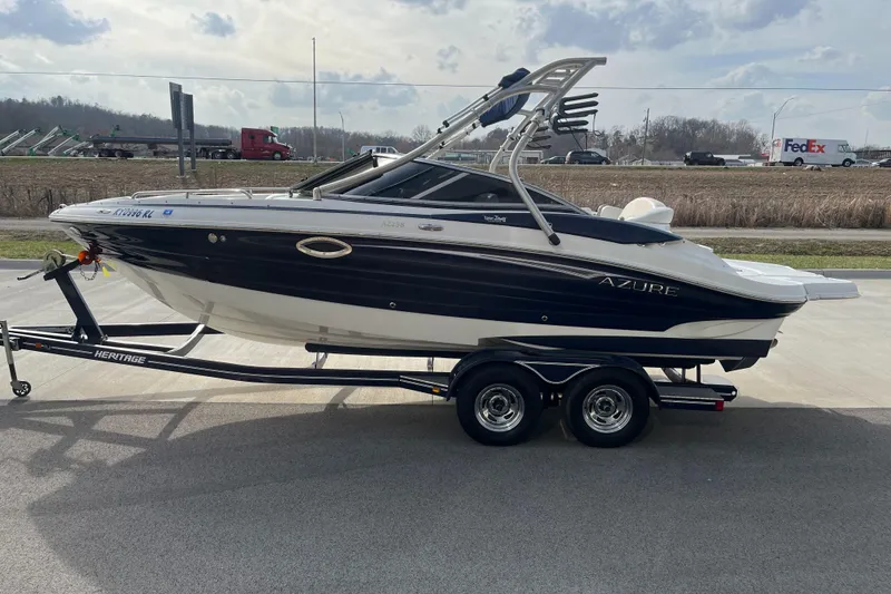 Slide: The Image of 2013 Azure AZ238 boat on trailer, parked near highway with trucks in background. - 5