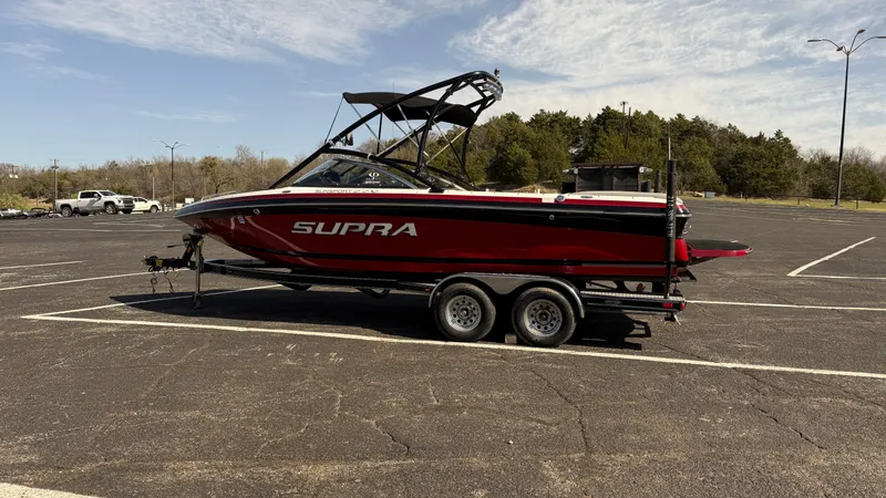 Slide: The Image of 2007 Supra Sunsport 22 V boat on trailer in parking lot, red and black design. - 6