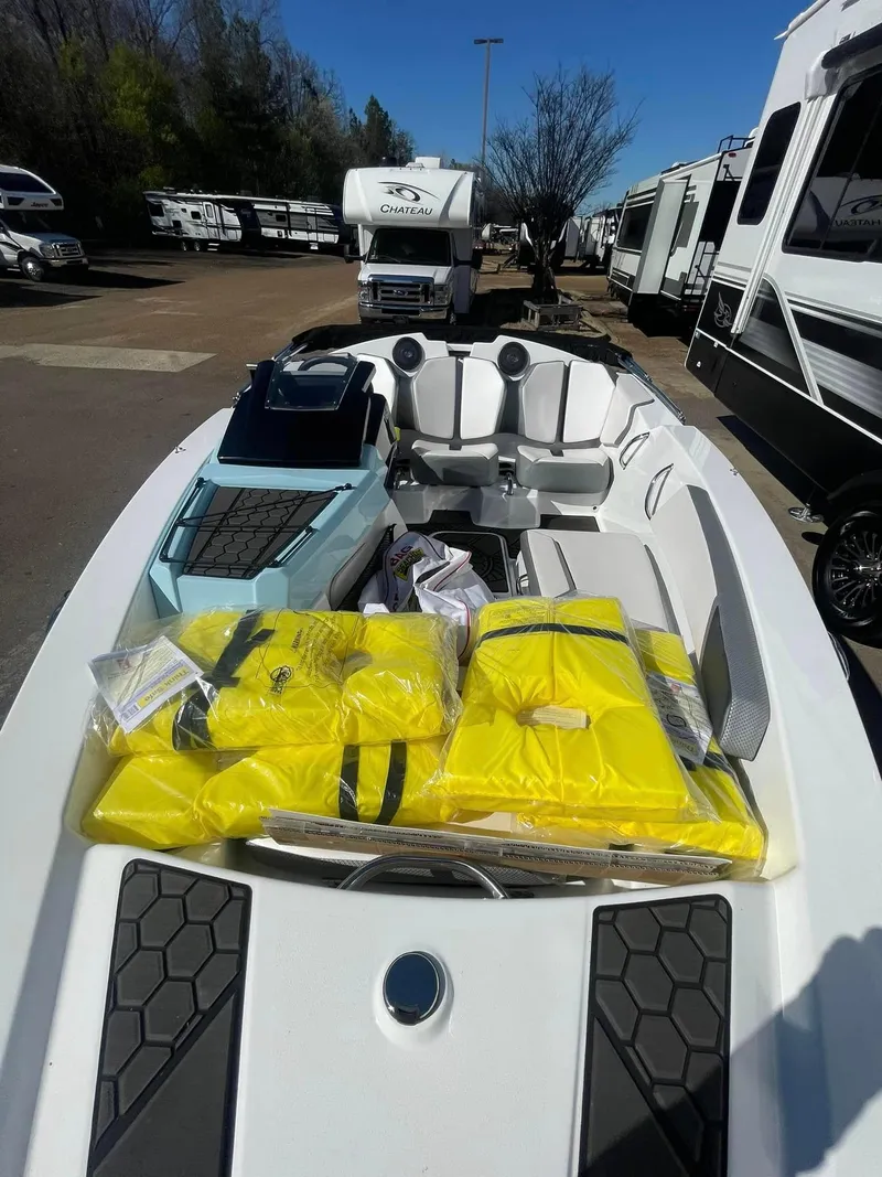 Slide: The Image of 2022 Scarab 165 SE boat with yellow life jackets, parked near RVs. - 6