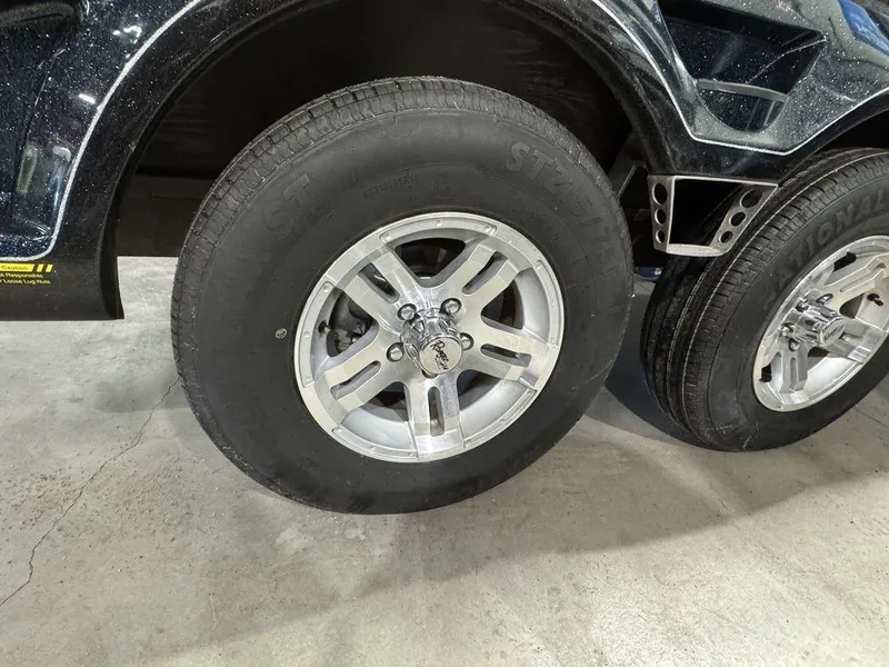 Slide: The Image of 2018 Ranger 212LS trailer wheel with silver alloy rim and black tire on concrete floor. - 15