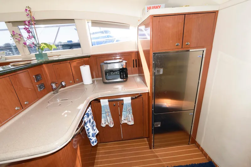 Slide: The Image of 2002 Sea Ray 480 Motor Yacht kitchen with wooden cabinets and stainless steel appliances. - 18