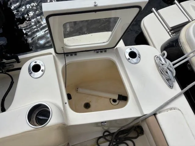 Slide: The Image of 2022 Scout 215 XSF boat with open storage compartment and fishing rod holders. - 12