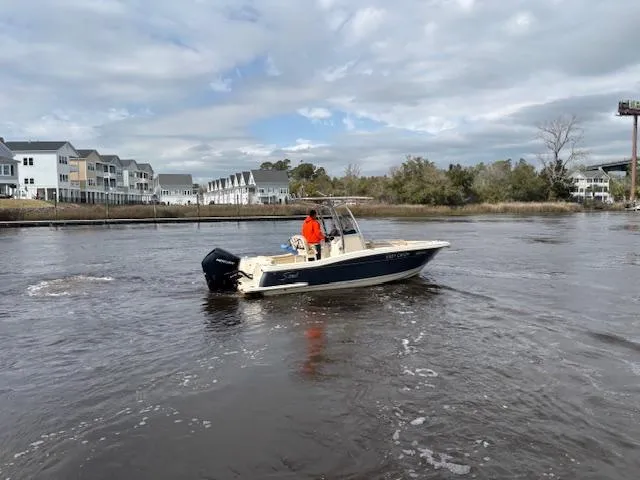 Slide: The Image of 2022 Scout 215 XSF boat cruising on a river near residential buildings. - 3
