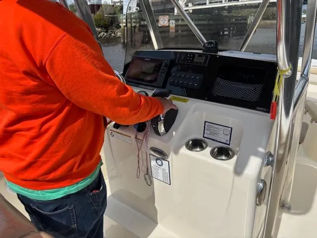 Slide: The Image of Person operating 2022 Scout 215 XSF boat's helm with modern controls. - 37