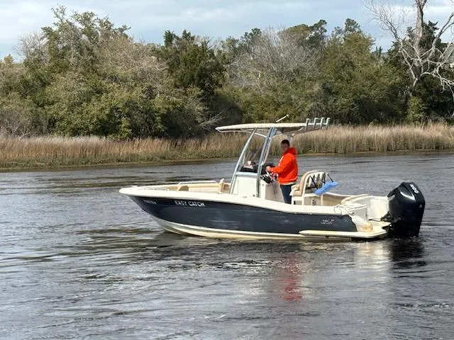 Slide: The Image of 2022 Scout 215 XSF boat on a calm river with trees in the background. - 5