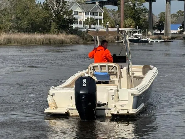 Slide: The Image of 2022 Scout 215 XSF boat navigating a calm river with a person in an orange jacket. - 9