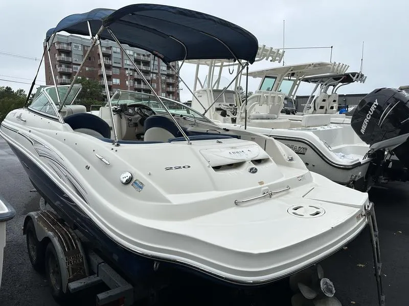 Slide: The Image of 2006 Sea Ray 220 Sundeck boat with blue canopy, parked on trailer. - 10