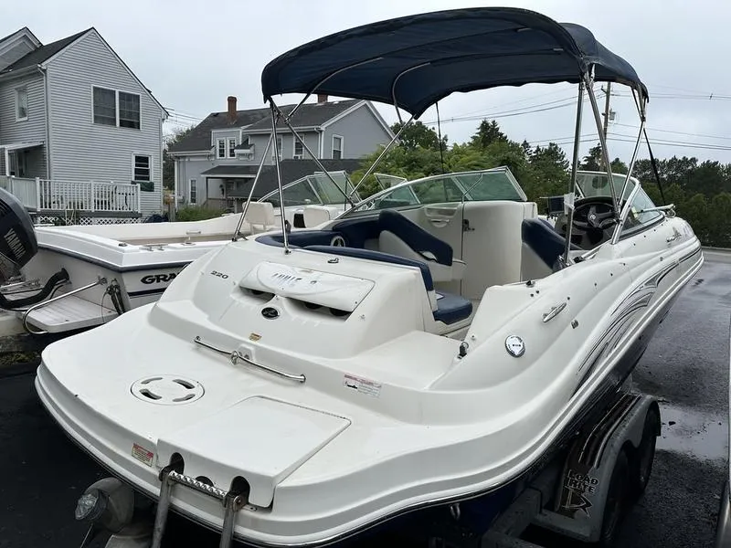 Slide: The Image of 2006 Sea Ray 220 Sundeck boat with canopy, parked on a trailer in a residential area. - 8