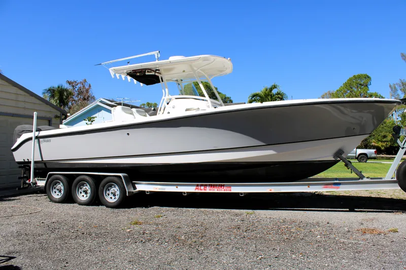 Slide: The Image of 2008 Edgewater 318CC boat on a trailer, parked outdoors under clear blue sky. - 0