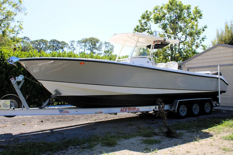 Slide: The Image of 2008 Edgewater 318CC boat on trailer, parked outdoors near trees and a shed. - 1